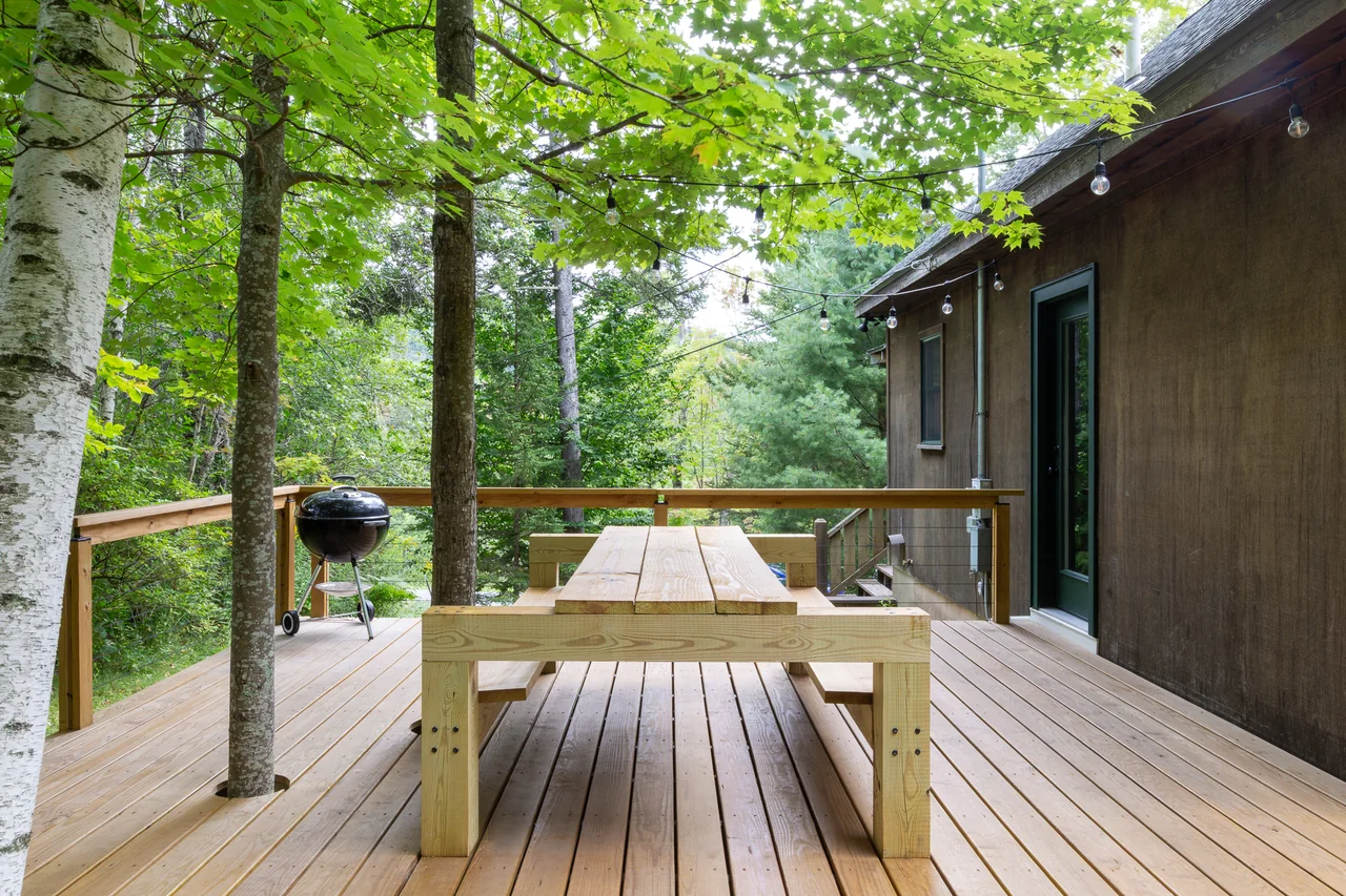 A timber deck and picnic table nestled among trees at Catskills Cabin
