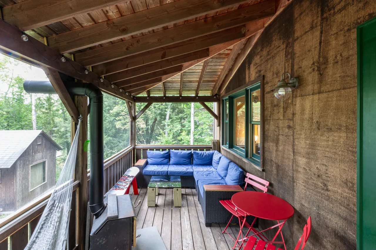 A screened porch with blue seating and a red table at Catskills Cabin