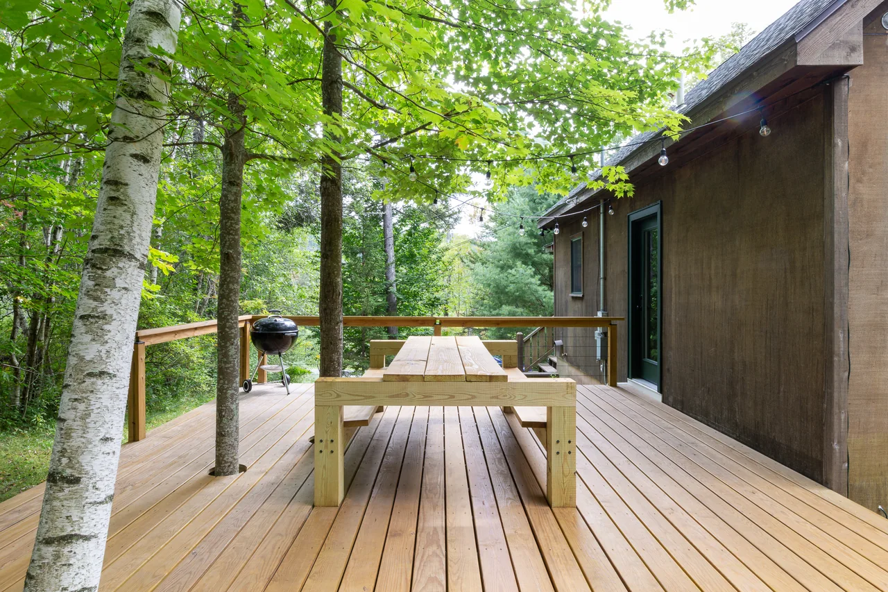 The cabin deck with dining table and mature trees