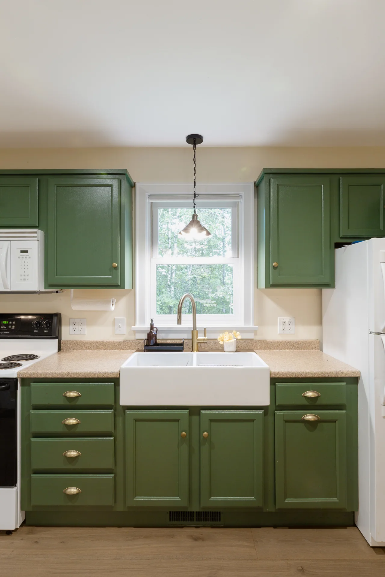 Green cabinetry and a white kitchen sink